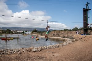 Tirolina sobre el lago de Finca Daroca con kayaks y rocódromo al fondo