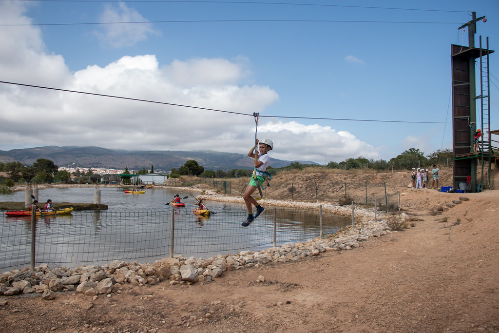 Tirolina sobre el lago de Finca Daroca con kayaks y rocódromo al fondo